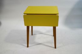 A vintage yellow formica kitchen table with drop ends on tapering legs, 75cm high x 89cm wide x 60.