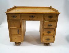 A pine kneehole desk with an arrangement of six drawers and single cupboard, raised on turned feet,