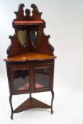 An Edwardian mahogany corner standing cupboard with raised back,