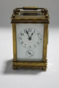 A small brass carriage clock, the enamel dial with subsidiary alarm,