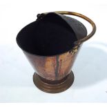A copper coal scuttle with swing handle of oval form, embossed with flowers on flared foot,