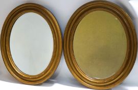A pair of oval Regency style wall mirrors, with bevelled glass,