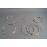 A torque bangle, a trinity bangle; and two pairs of earrings,