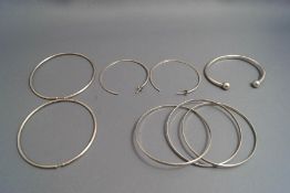 A torque bangle, a trinity bangle; and two pairs of earrings,