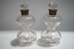 A pair of silver collared glass decanters of wasted form, with stoppers,