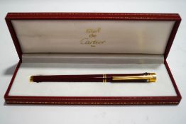 A Must de Cartier fountain pen, maroon red body and the Cartier Trinity rings to the cap top,