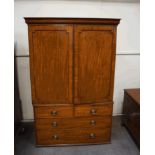 A George III mahogany linen press, the cupboard doors enclosing four trays, over a four drawer base,