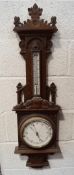 A late Victorian oak cased barometer and thermometer, carved with gothic and heraldic decoration,