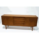 A mid-20th century teak sideboard with four central drawers flanked by cupboards with sliding doors,