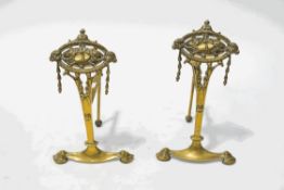 A pair of brass firedogs, cast in neo-classical style with rams heads and husked swags,