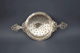 An Arts and crafts silver tea strainer, by CJP, London 1909, with wire work handles, 14 cm across,