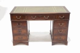 A mahogany pedestal desk with gilt tooled leather inset top with an arrangement of nine drawers on