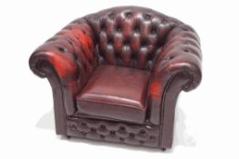 A red leather armchair with button back and arms