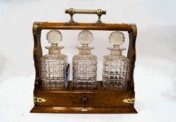 An early 20th century oak three bottle tantalus,