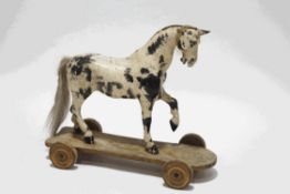 A late 19th century carved and painted childs' pull along horse with stirrups,