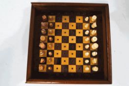 An early 20th century travelling chess set, within a mahogany box, the chess pieces of carved bone,