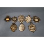 A collection of right silver watch fobs, including one depicting a runner,