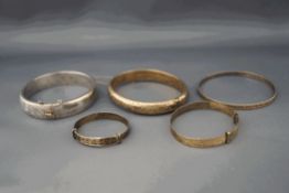 A collection of five bangles, comprising two hallmarked silver hinged bangles,