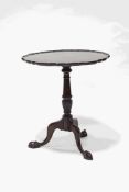 A George III style mahogany tilt top table, the piecrust top upon a turned column and claw feet,