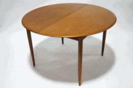 A Danish teak circular extending dining table by Mogens Kold, with one intragal leaf,