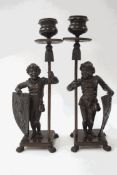 A pair of 19th century bronze candlesticks in the form of figures holding a sconce,