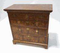 A walnut chest of three short and three long drawers with brass handles and bracket feet (probably
