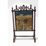 A Victorian rosewood firescreen with tapestry panel of a Continental town and river scene,