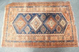 A Middle Eastern rug, the central field with ten diamond motifs on a blue ground,