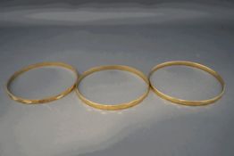 A collection of three 9 carat gold stiff bangles, 21.