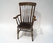 An early 20th century stick back elbow chair with solid seat and turned legs,