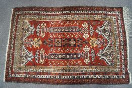 A Persian Beluchi rug, with multiple geometric motifs on a red ground within five borders,