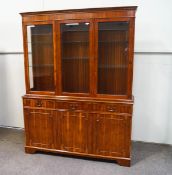 A modern yew wood display cabinet with three drawers above three cupboard doors on plinth base,