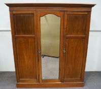 An Edwardian mahogany triple wardrobe, the central mirrored door flanked by two panelled doors,