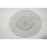 An Italian glass plate, spirally moulded with spiral blue,