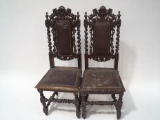 A pair of Victorian oak dining chairs cared with lions flanking a crest with barley twist uprights