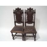 A pair of Victorian oak dining chairs cared with lions flanking a crest with barley twist uprights