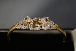 A diamond and ruby panthers bangle, stamped '9K',