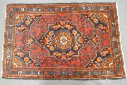 A rug with central medallion on a red field with black ground spandrels within three boards,