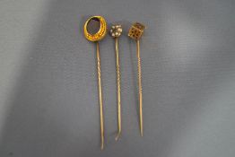 A garnet set stickpin; another stick pin with a pierced cube motif;