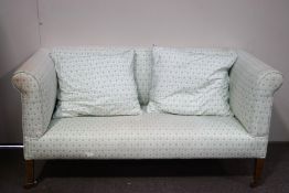 An Edwardian two seat sofa with square tapering legs with brass and ceramic casters,