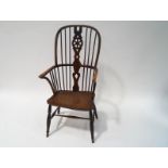 A 19th century Windsor elbow chair with pierced splat, the solid seat with old blacksmith's repair.