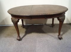 An Edwardian mahogany oval dining table with one loose leaf on carved cabriole legs with ball and