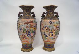 A pair of large Japanese satsuma style earthenware vases, each with raised decoration,
