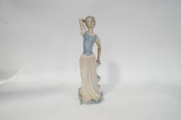 A Tengra figure of a young lady holding the hem of her skirt, decorated in Lladro style,