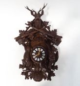 A Black Forest triple weight cuckoo clock with carved Stag head crest above two crossed guns,