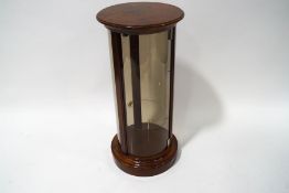 A mahogany framed cylindrical display cabinet with adjustable shelf on plinth base,