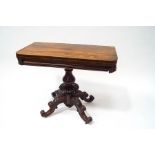 A Victorian rosewood card table with turned baluster pedestal and four carved scroll legs with