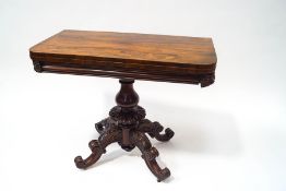 A Victorian rosewood card table with turned baluster pedestal and four carved scroll legs with