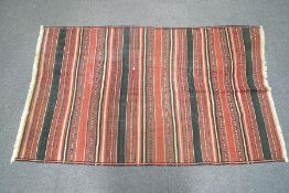 A kilim rug with repeating stripes in red, black and beige, 266cm long x 168cm wide.
