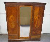 An Edwardian mahogany and marquetry triple wardrobe, the central mirrored door enclosing a shelf,